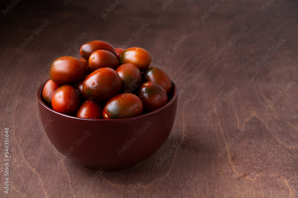 red tomatoes in a brown bowl. Fresh cherry tomatoes with water drops on wooden background. copy space red tomatoes in a brown bowl. Fresh cherry tomatoes with water drops on wooden background. copy space
