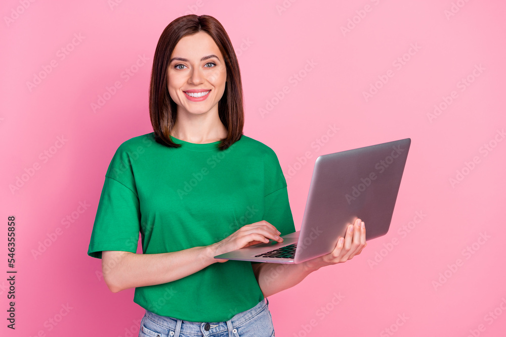 Photo of pretty positive lady hold wireless netbook toothy smile isolated on pink color background Photo of pretty positive lady hold wireless netbook toothy smile isolated on pink color background