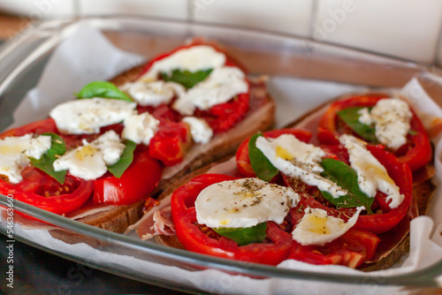 Ham, tomato, mozarella and basil leaves toasts