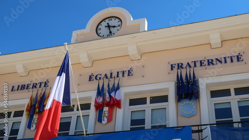 Façade de la mairie / hôtel de ville de Saint-Mandrier-sur-Mer, avec des drapeaux provençaux, français et européens et la devise nationale "Liberté, égalité, fraternité" (France)