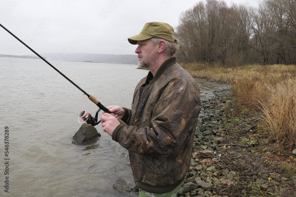A fisherman, a man catches fish with a fishing rod, from the bank of the river. A fisherman, a man catches fish with a fishing rod, from the bank of the river.