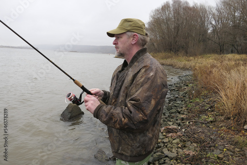 A fisherman, a man catches fish with a fishing rod, from the bank of the river.