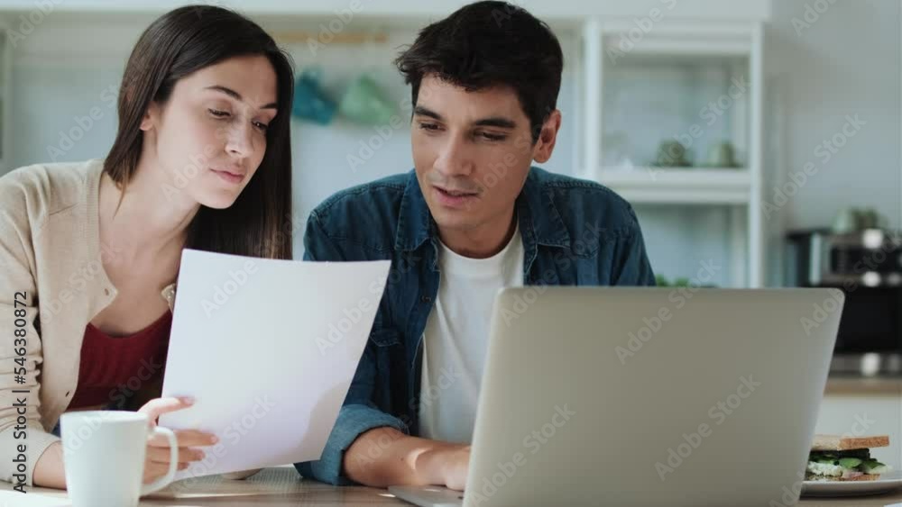 Video of beautiful lovely couple using their laptop and digital tablet to searching voyage in the kitchen at home. Video of beautiful lovely couple using their laptop and digital tablet to searching voyage in the kitchen at home.