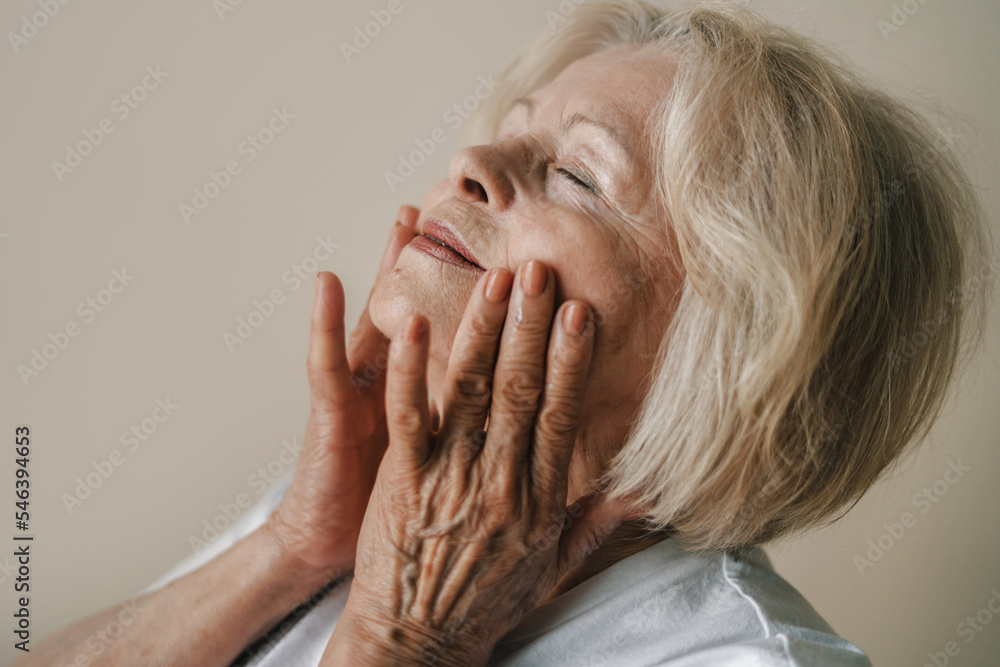 Portrait of senior woman applying anti-aging cream on face, isolated over gray background. Closeup portrait. Natural skin care cosmetic. Beauty treatment Portrait of senior woman applying anti-aging cream on face, isolated over gray background. Closeup portrait. Natural skin care cosmetic. Beauty treatment