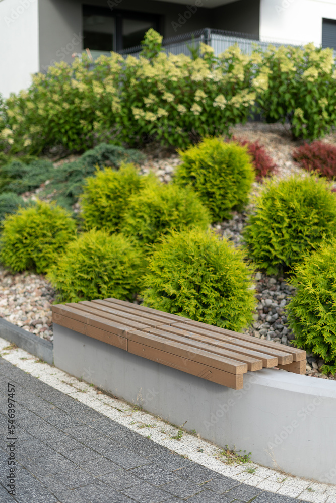 Concrete bench with wooden slats for sitting near residential building