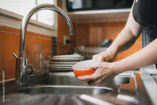 Woman washing dishes in kitchen sink, close up of hands. photo