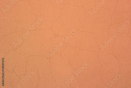 Photo of a peach colored concrete wall with many cracks in the plaster.
