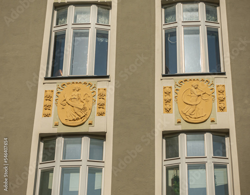 Estonia, Tallinn - July 21, 2022: Tikk 59 street in old town. Closeup of 2 mural sculptures depicting females on historic KGB building with windows. photo