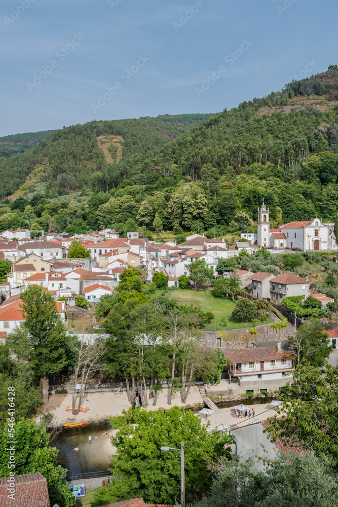 Architecture of the village with houses, church and trees with river beach of Peneda in aerial view and mountain in the background, Góis PORTUGAL