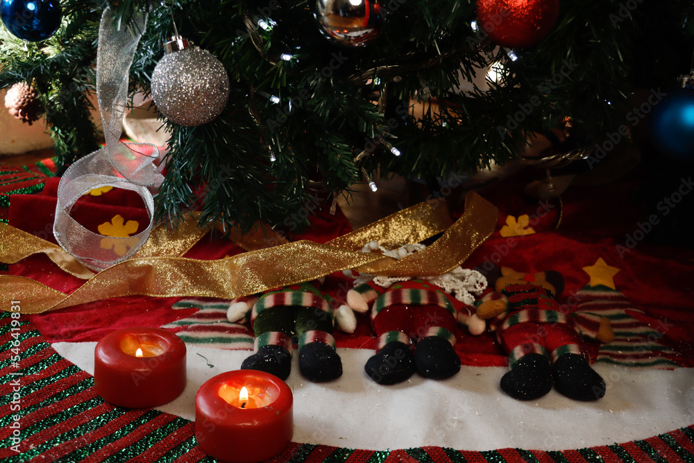 Burning candles on Christmas decorations at the foot of a Christmas tree decorated with spheres
