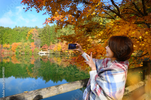 秋の季節を自撮りをしたり風景を撮影する女性