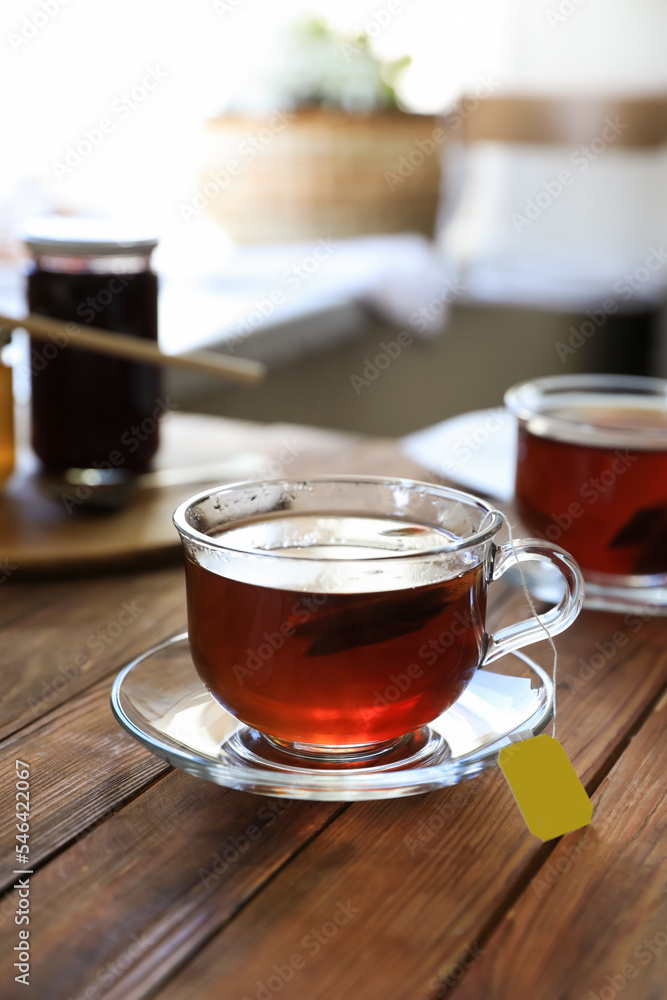 Tea bag in glass cup on wooden table indoors Tea bag in glass cup on wooden table indoors