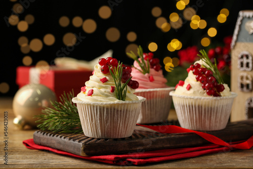 Delicious cupcakes and Christmas decorations on wooden table