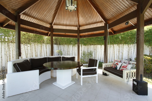 Large backyard gazebo with table and cushioned and hanging chairs © Vincent