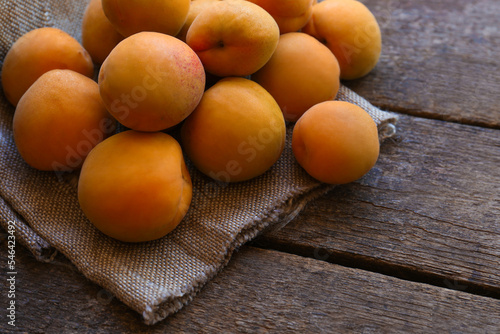 Delicious ripe apricots with napkin on wooden table, closeup