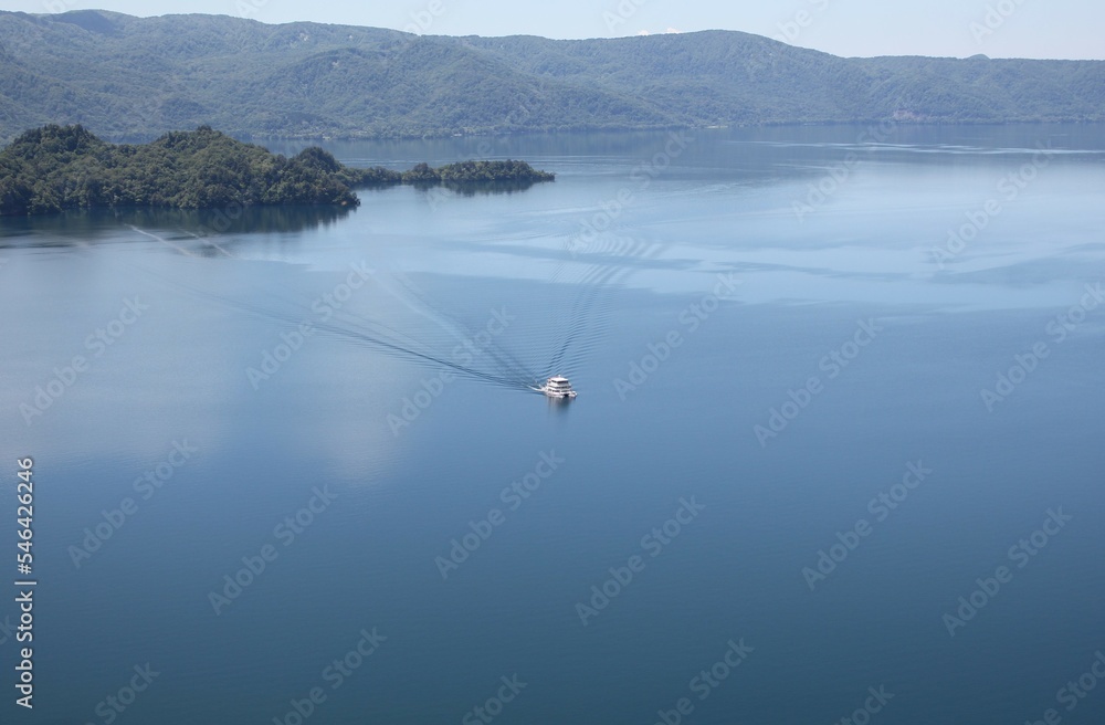 A sightseeing boat cruising around Lake Towada in Japan - from a observation deck view A sightseeing boat cruising around Lake Towada in Japan - from a observation deck view