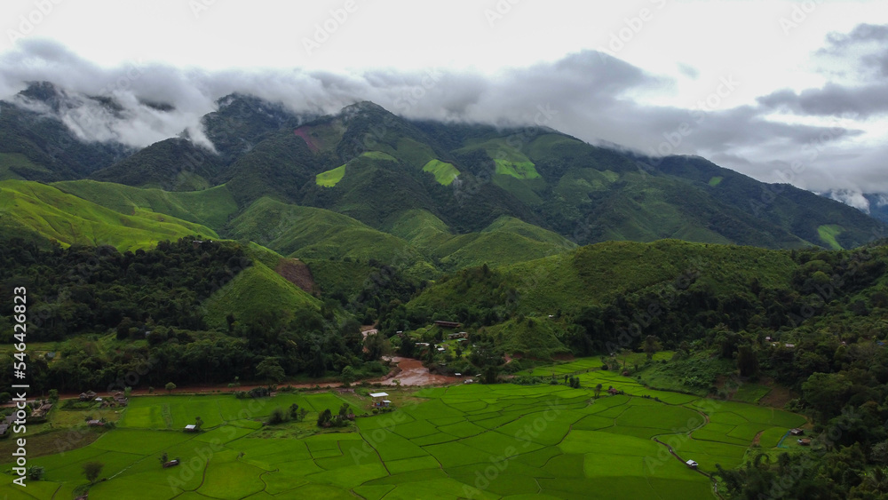 Aerial view. The beautiful mountains with clouds and green rice field.