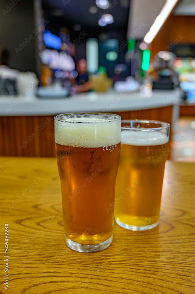 Fresh draught lager or IPA beer is glass served in indoor cafe close up, pint of beer Fresh draught lager or IPA beer is glass served in indoor cafe close up, pint of beer