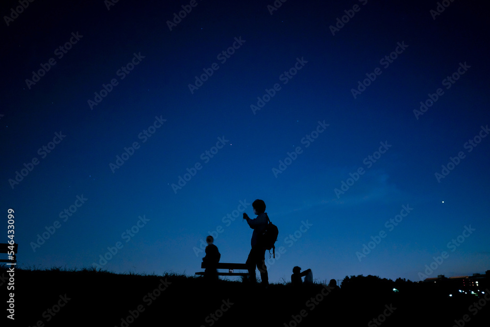 夜の丘を歩く人々