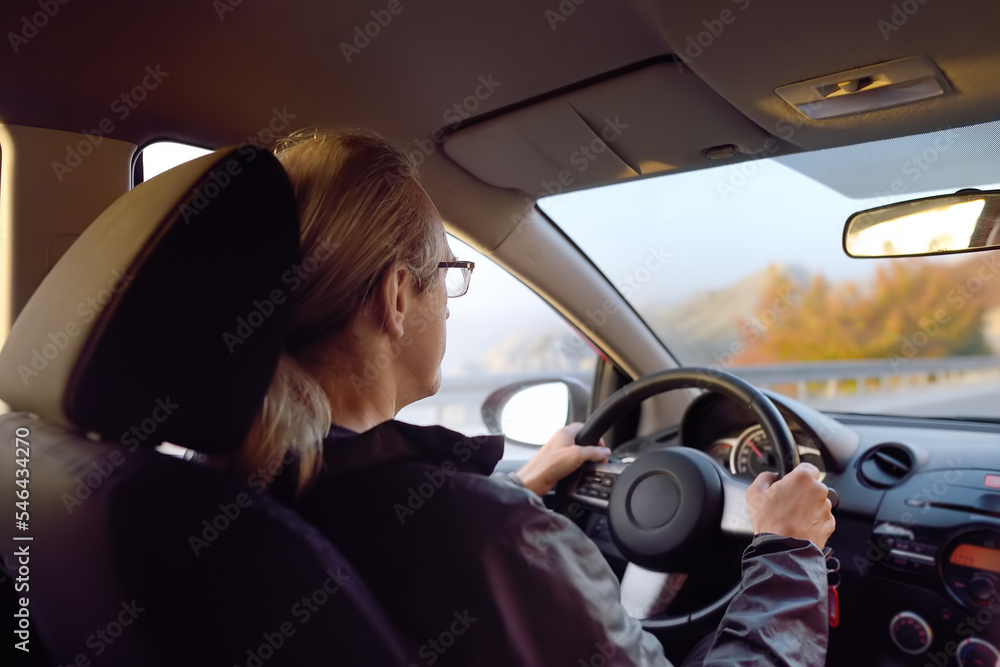 Mature man driver riding a car. Driving by mountain road on autumn day. Inside view.
