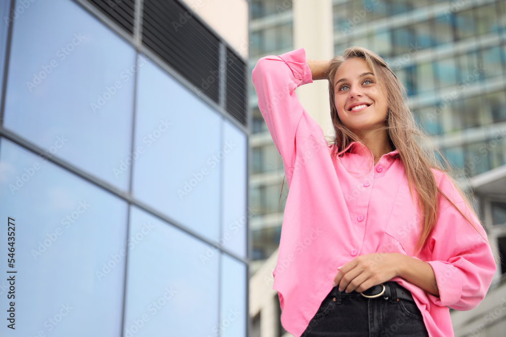 Portrait of beautiful young woman near building outdoors, low angle view. Space for text