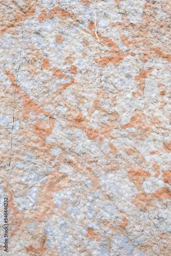 Closeup of hand-hewn stone wall, light colored stone in yellows, oranges, and browns 
