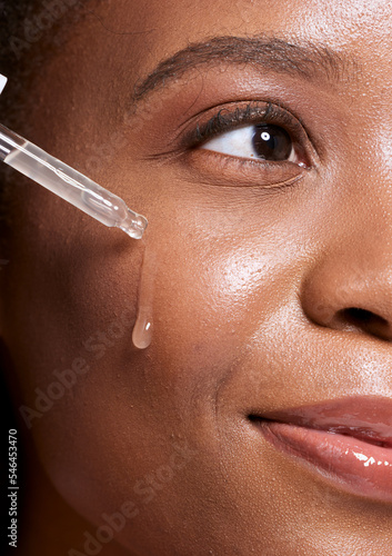 Black woman, dropper and facial skincare cosmetics for beauty, hydration or oil treatment for healthy face. Closeup of African American female applying serum to cheek for skin hydrate, glow or shine