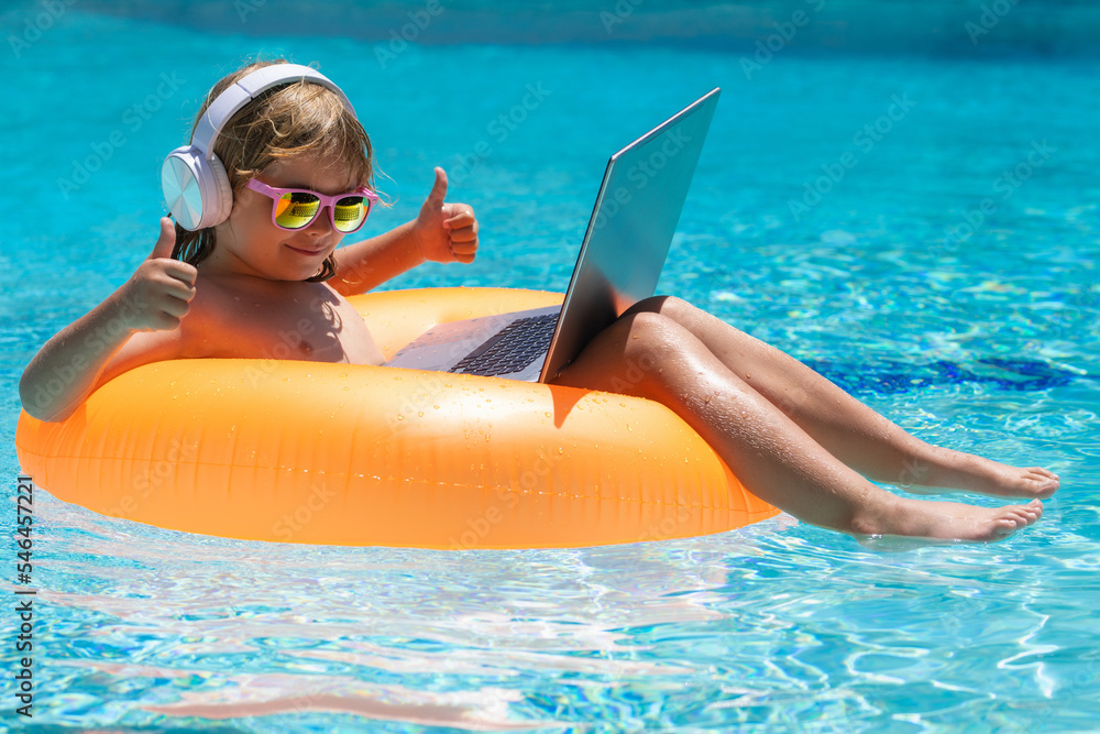 Little businessman working on tropical beach. Summer business. Child remote  working on laptop in pool. Little business man working online on laptop in  summer swimming pool water. Stock Photo