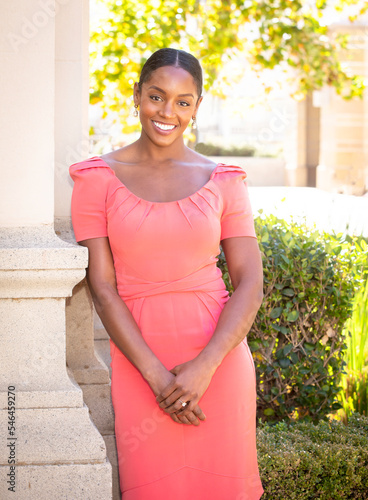 Vertiical image of an African American woman wearing a pink dress in an outdoor setting photo