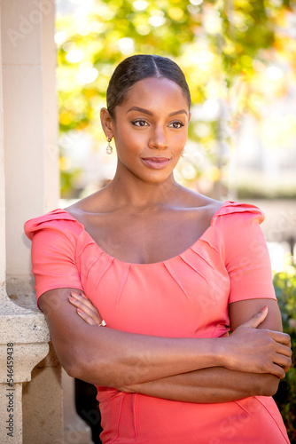 Vertiical image of an African American woman wearing a pink dress in an outdoor setting photo