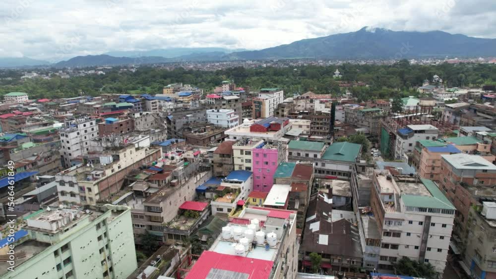 Aerial drone shot of building with mountains in background with tress and clouds in India