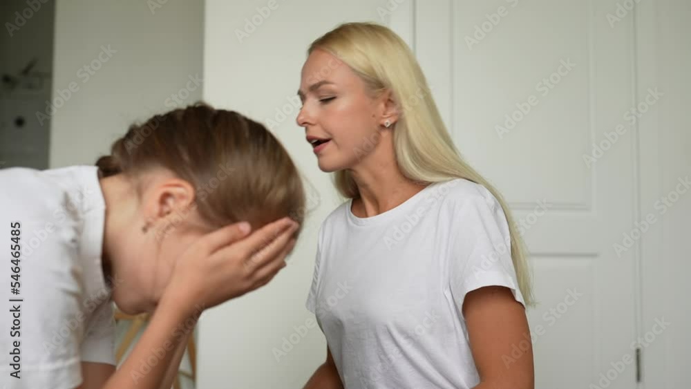 Close-up side view of little girl crying covering face with palm while angry young mother scolding, raising voice, scream at stubborn difficult little child daughter at home. Shooting in slow motion. Close-up side view of little girl crying covering face with palm while angry young mother scolding, raising voice, scream at stubborn difficult little child daughter at home. Shooting in slow motion.