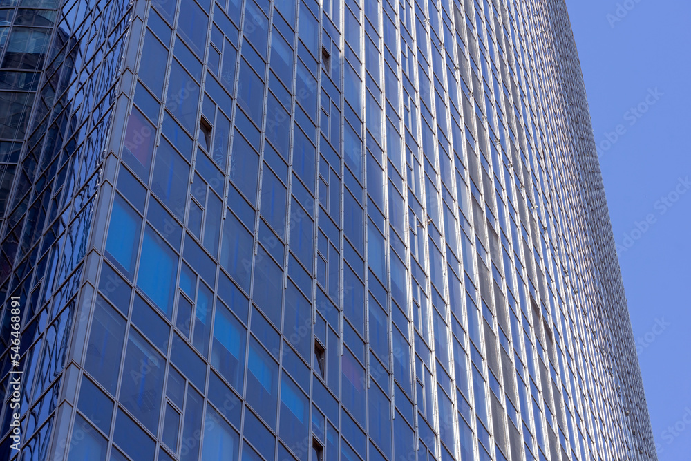 Glass building facade. Modern office building facade. Tall business center with a glass facade. Construction of a glass facade structure. The glare of the sun on the glass wall of a skyscraper Glass building facade. Modern office building facade. Tall business center with a glass facade. Construction of a glass facade structure. The glare of the sun on the glass wall of a skyscraper