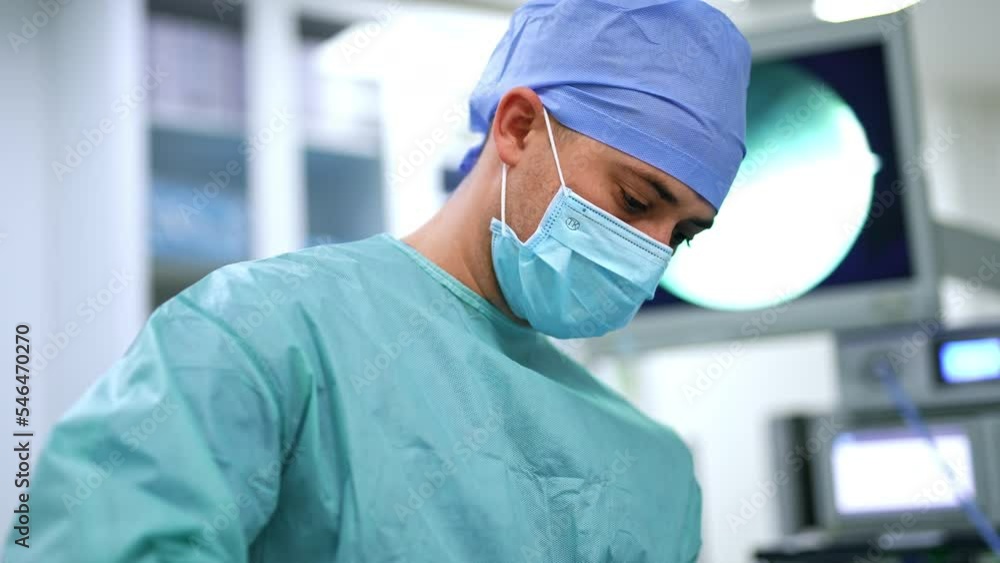 Male medical assistant holding needle and forceps to sew the patients. Blurred backdrop at modern surgery room. Male medical assistant holding needle and forceps to sew the patients. Blurred backdrop at modern surgery room.