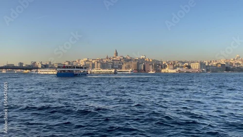 View of the Bosphorus strait with ferry boats and Karakoy district on background at sunset in Istanbul city. Popular touristic destination in Turkey photo