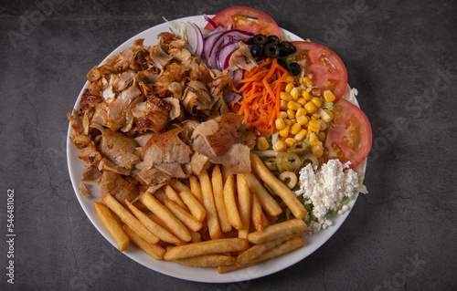 Doner kebab or gyros on a plate with french fries and salad.