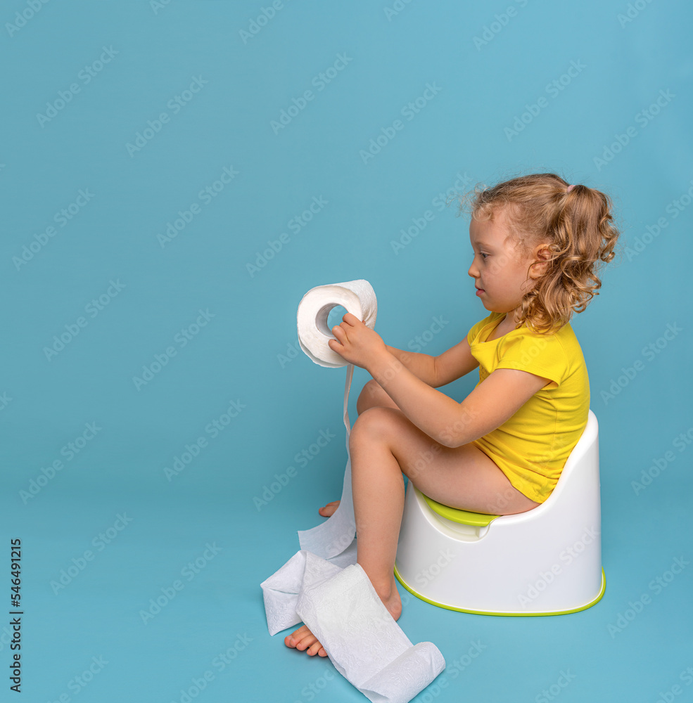 A child on the potty plays with toilet paper. Toilet training. Stock