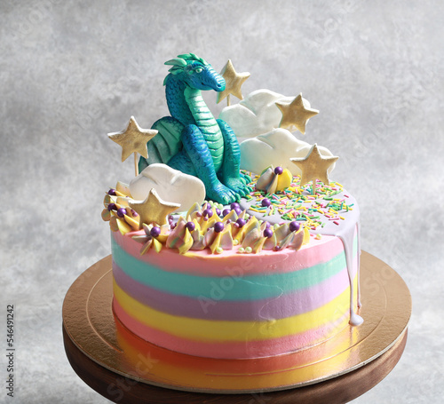 A beautiful fairy cake for children with a dragon in the clouds with stars and colorful cream