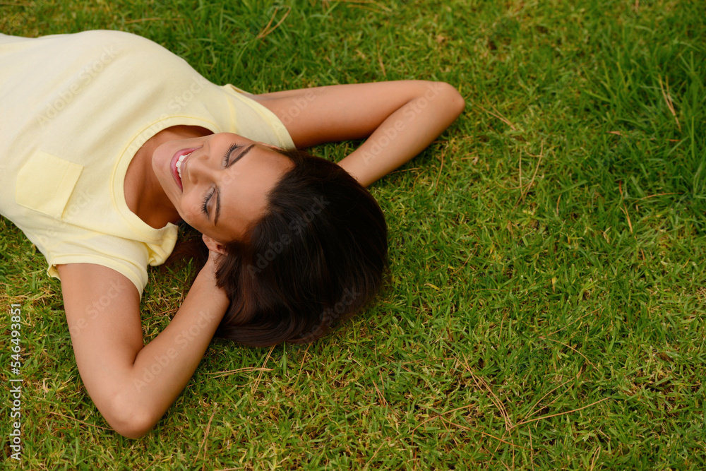 Happy woman relax on park grass, garden and nature, freedom or rest on summer lawn with mockup. Above of young girl lying on green field outdoor in sunshine for calm, peace and mental health wellness Happy woman relax on park grass, garden and nature, freedom or rest on summer lawn with mockup. Above of young girl lying on green field outdoor in sunshine for calm, peace and mental health wellness