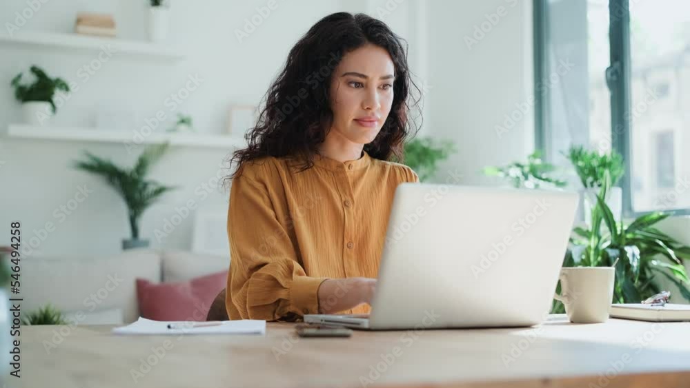 Video of beautiful business woman working with laptop in living room at home.
