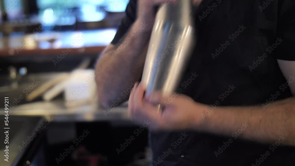 Bartender mixing drinks in shaker while making cocktails at bar counter close up Bartender mixing drinks in shaker while making cocktails at bar counter close up
