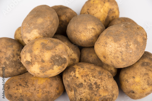 Stack of unwashed potatoes on a white background