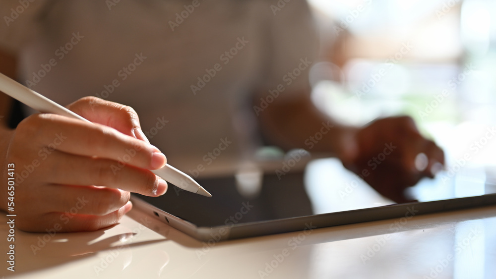 Asian female using her digital tablet and stylus pen to design her artwork. cropped shot