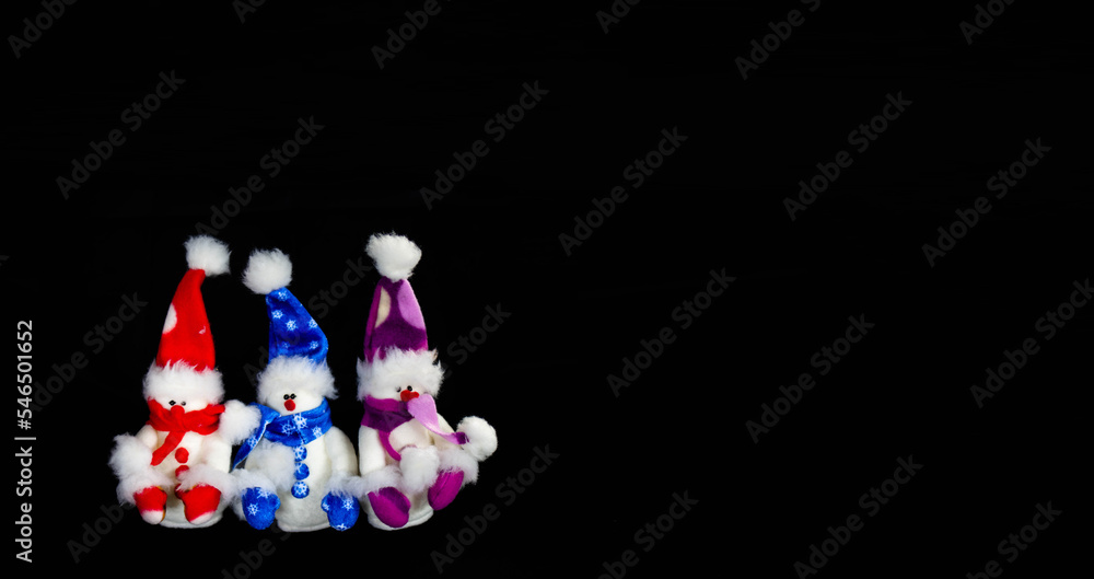 Banner with three handmade toy snowmen with hats and scarves on a black background. Christmas and New Year concept Banner with three handmade toy snowmen with hats and scarves on a black background. Christmas and New Year concept