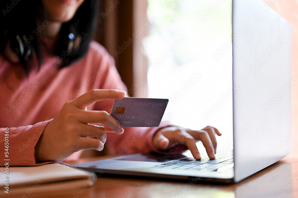 Woman holding her credit card and typing on laptop keyboard. cropped shot Woman holding her credit card and typing on laptop keyboard. cropped shot