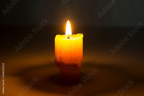 Old burning candle with a flame. Melted wax