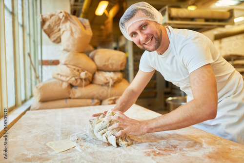 Bäcker knetet Teig als Vorbereitung zum Brot backen photo