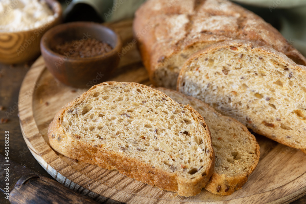 Bread from whole wheat grains, wheat bran, seeds, bio-ingredients over rustic table background, healthy lifestyle.