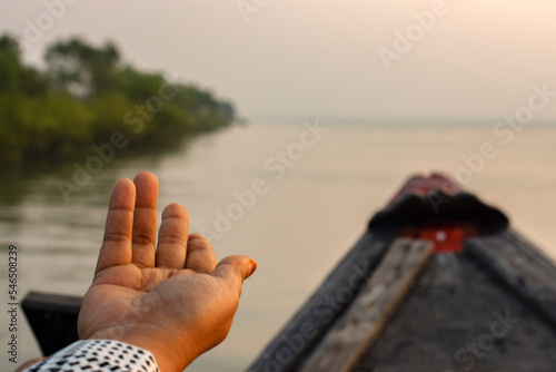 An young solo traveler showing her hands on the adge of a country boat looking at the mangrove forest of Sundarban Tiger Reserve. photo