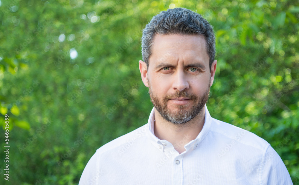 Portrait of handsome guy with unshaven face in white shirt natural background, copy space